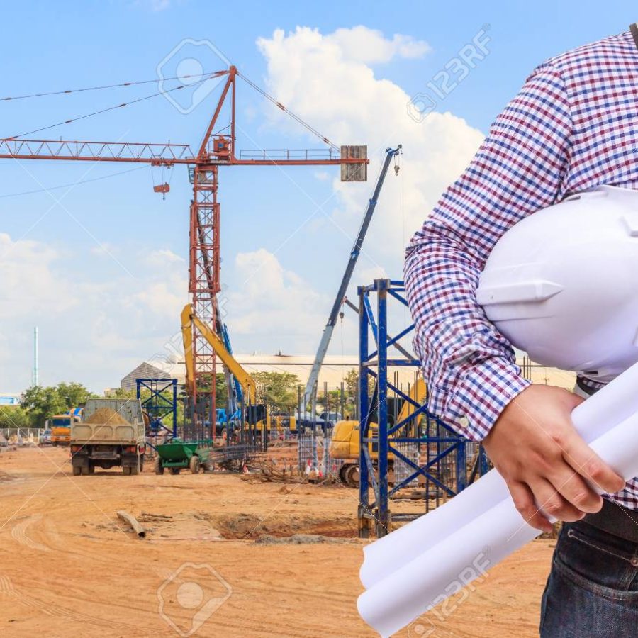 Civil Engineer holding in hand a helmet safety and blueprints with background of construction site in blue sky
